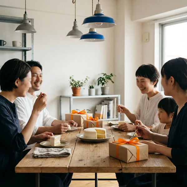 Familie an Holztisch mit Vanilletorte und Geschenken in warmem, minimalistischem Wohnzimmer – geburtstagsgeschenk ideen