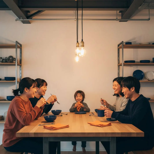 Kleine Familie oder Freunde am Esstisch mit industriellem Charme, warmem Licht und Holz‑/Metalldetails, teilen ein Geschenk in einer natürlichen, ungestellten Szene.