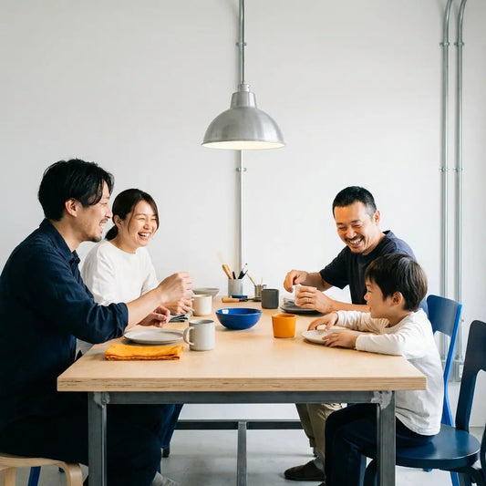 Kleine Familie am Holz-Esstisch lacht und teilt Geschenke in warmem, minimalistischem Wohnraum mit Metalldetails – geschenke erzieher