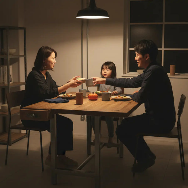 Abendliche Familienszene mit warmem Licht, Holz- und Metalldetails, das Produkt aus den Referenzfotos im Vordergrund – ideal als geschenke für jemanden der alles hat.