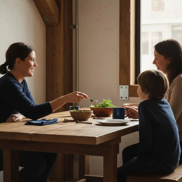 Kleine Gruppe an Esstisch mit warmen Holz- und Metallakzenten, Hände greifen nach Tellern – authentisches Zusammensein, geschenke für den arbeitgeber