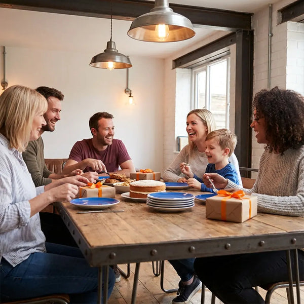 Gemütlicher Essbereich mit Holztisch, Metalldetails und liebevoll verpackten geschenken für schwiegereltern, einfache Vanilletorte und intime Familienatmosphäre.