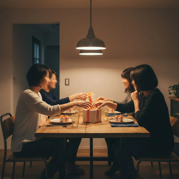 Gemütliches Esszimmer mit Holz­tisch und Händen, die nach kleinen Geschenkboxen greifen – geschenke zur goldenen hochzeit im Fokus, warmes Licht, leichter Industriecharme