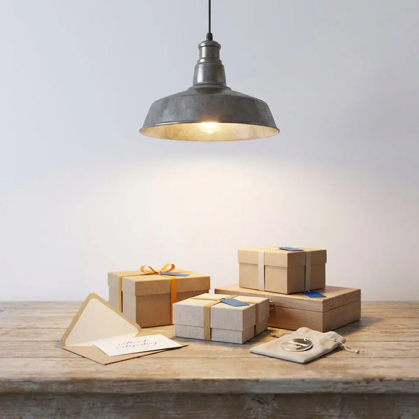 Heimischer Holztisch mit sorgfältig arrangierten Geschenken zur Taufe, personalisierter Metallanhänger auf Leinenbeutel, warmes Licht und dezente Akzente