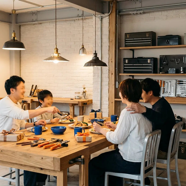 Kleine Familie am rustikalen Esstisch beim Auspacken von geschenkideen eltern; Fokus auf Hände, Teller, Holzoberflächen und sichtbare Metalldetails.