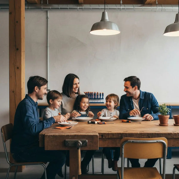 Kleine Familie lacht am Holz-Esstisch in warmem, leicht industriellem Zuhause – Geschenkideen Vater Geburtstag, authentisches Zusammensein ohne Text.