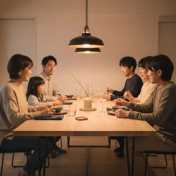Kleine Familie lacht am Esstisch mit Holzoberfläche und metallischen Akzenten, Hände greifen nach Tellern – jahrestag geschenke im warmen, minimalistischen, industriellen Zuhause.
