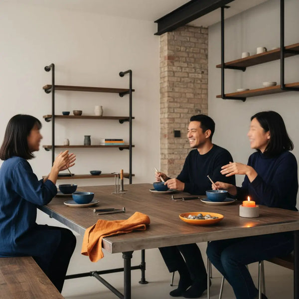 Warme, realistische Innenaufnahme: kleine Familie am Esstisch mit Metall- und Holzdetails, minimalistisch-industrieller Charme, Hände greifen nach Tellern, intimes Zusammensein. Was ist ein sinnvolles Hochzeitsgeschenk