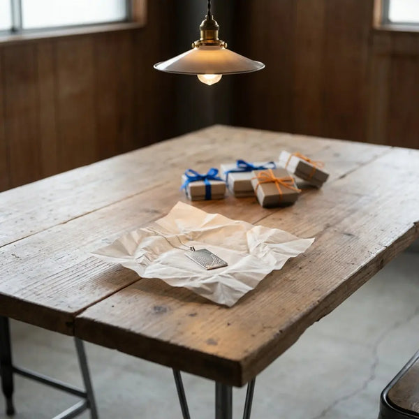 Gedeckter Holztisch mit mehreren Geschenkboxen, Seidenpapier und gravierbarem Metallanhänger im Fokus – was kann man für seine bff machen, minimalistisch, warme Industriestimmung