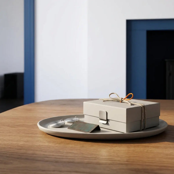 Holztisch mit sorgfältig arrangierten Metallgeschenken, Anhänger und kleinem Metallschild im hellen Wohnzimmer im Steelmonks-Stil. Welche Symbole bringen Glück?