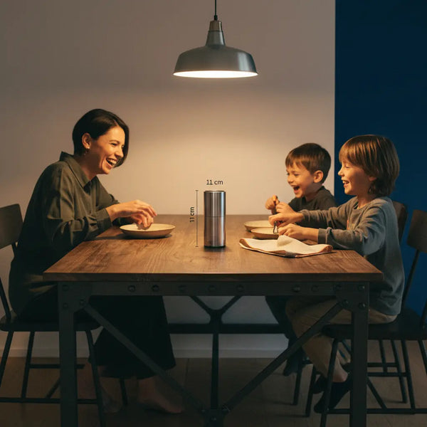 Intime Abend-Szene mit Familie um Tisch, das Produkt aus den Referenzfotos im Vordergrund, warme industrielle Stimmung und Holzoberflächen — wichtel ideen