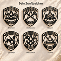 Sechs schwarze Zunftwappen aus Metall mit dem Namen MERTENS: Zimmerer, Dachdecker, Maurer, Elektriker, Mechaniker und Tischler. Überschrift: Dein Zunftzeichen.